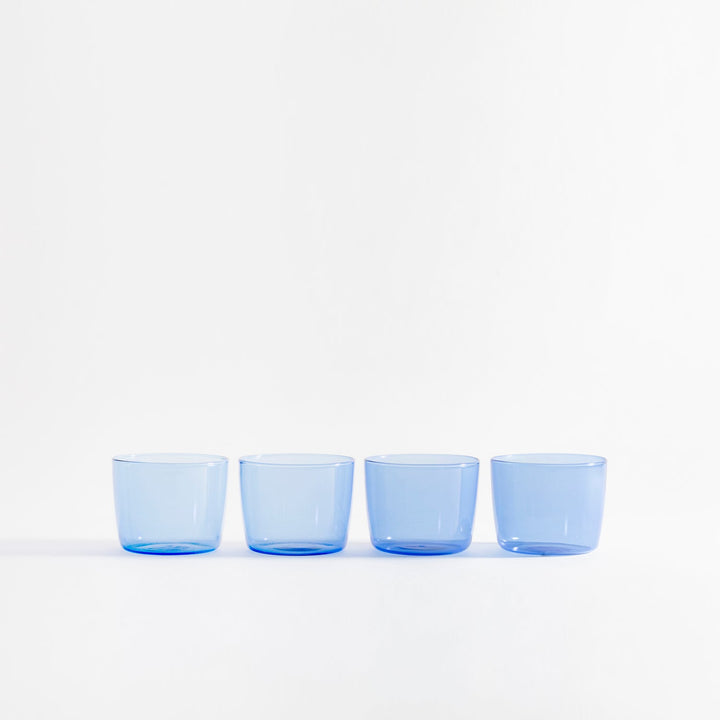 Four modern blue tinted glasses in straight line on table