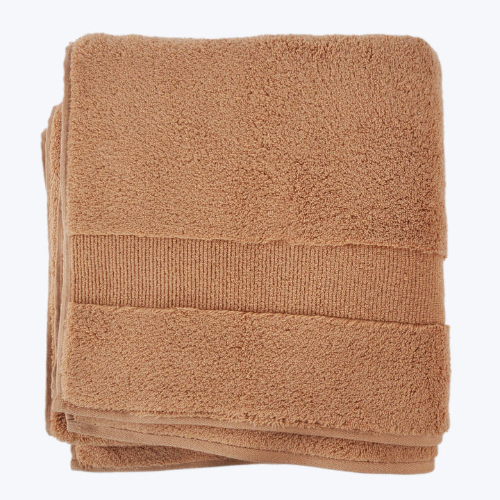 New terracotta plush towel with decorative band on white background.