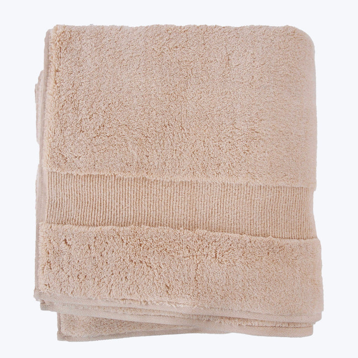 Neatly folded beige bath towel with decorative ribbed band detail.