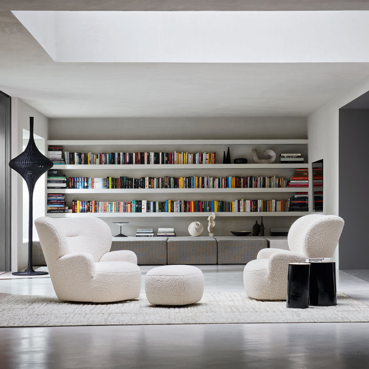 Modern living room with large bookshelf, white chairs, and elegant decor.