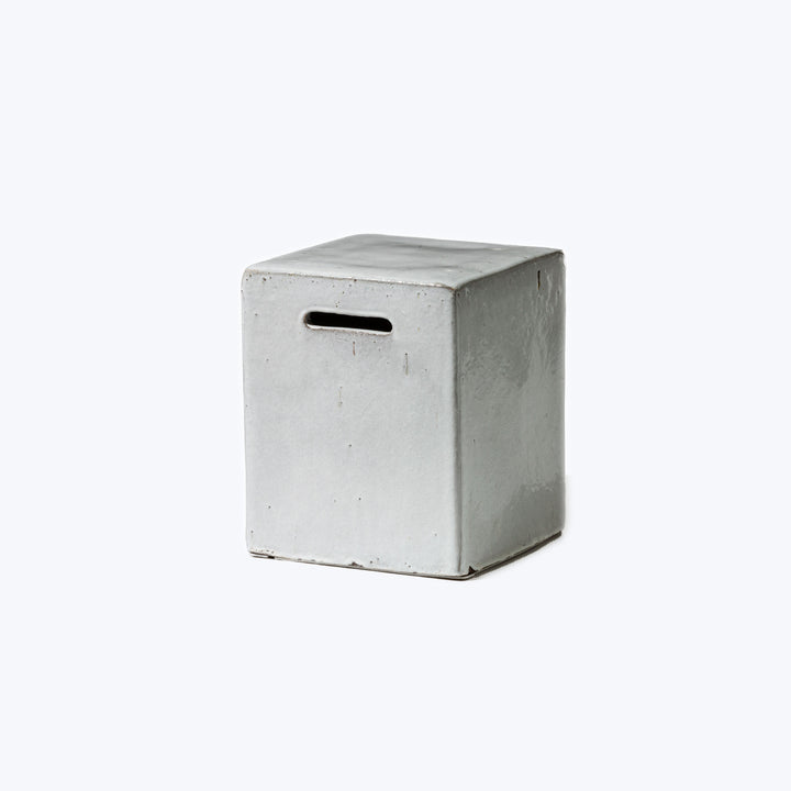 Minimalist cube-shaped container with slot, resembling concrete, against white background.