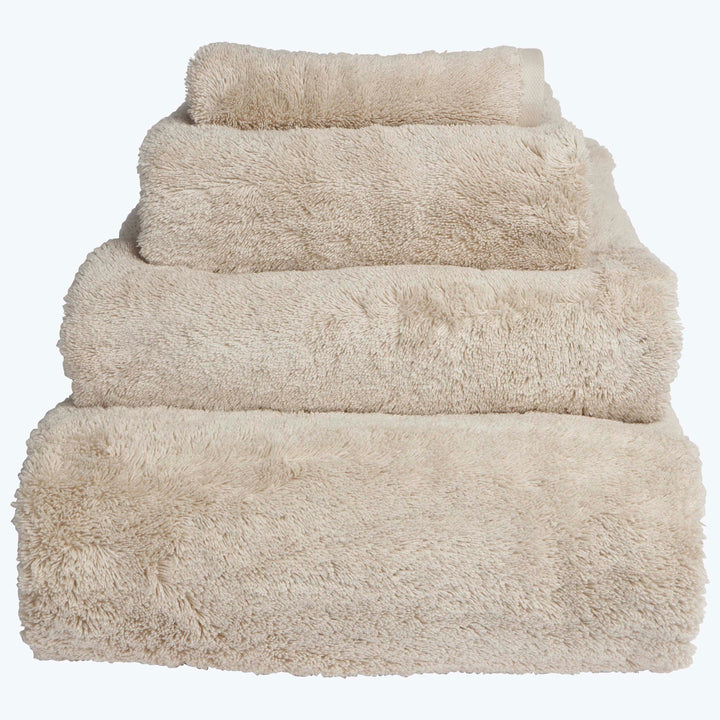Neatly stacked beige towels in descending order of size.