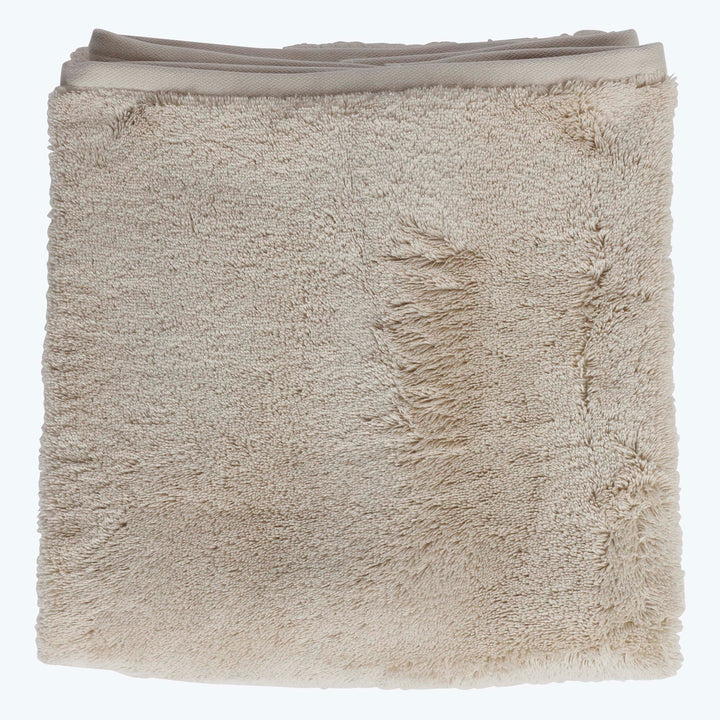 Soft, plush beige towel with neatly hemmed edges and texture.