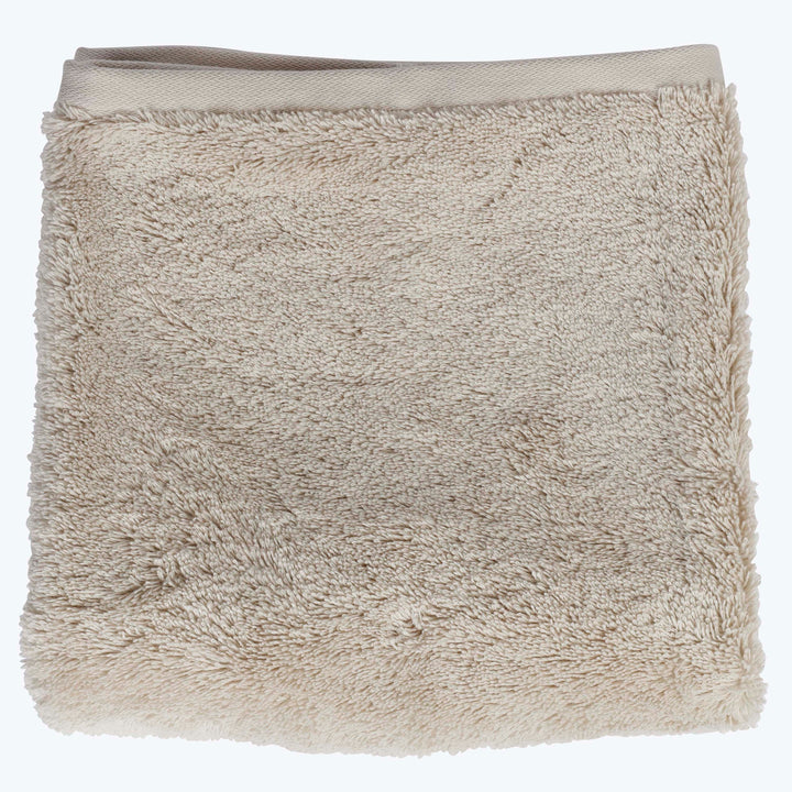 Folded beige bath towel with plush shaggy texture and trim