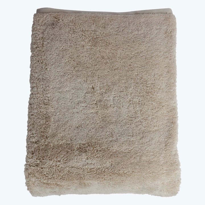 Neutral beige plush towel with textured surface and visible hem.