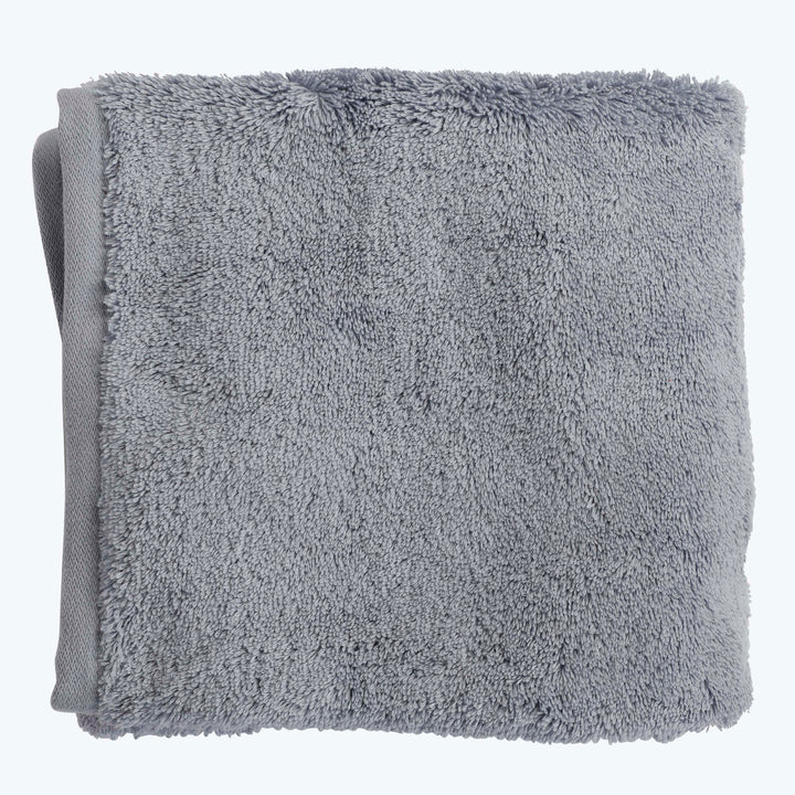 Folded grey towel with plush texture and visible fibers. Soft and fluffy for comfort and absorption. Clean and tidy.