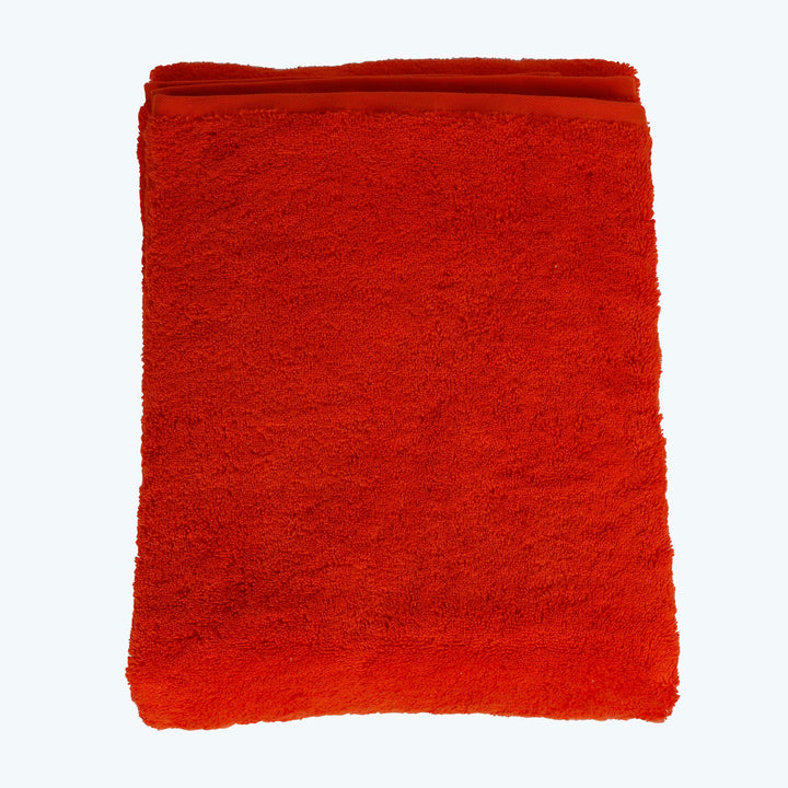 Bright red plush cotton towel neatly folded against white background.