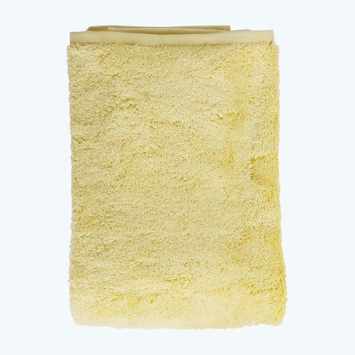 Soft and fluffy light yellow terry cloth bath towel folded.