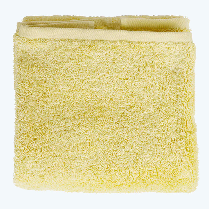 Soft, absorbent pale yellow towel folded neatly on white background.