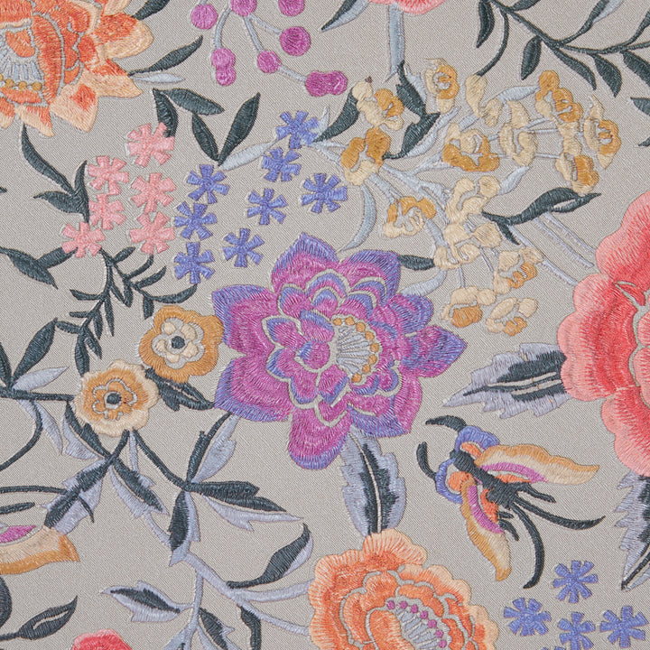 Colorful embroidered floral pattern on light fabric with intricate stitching.