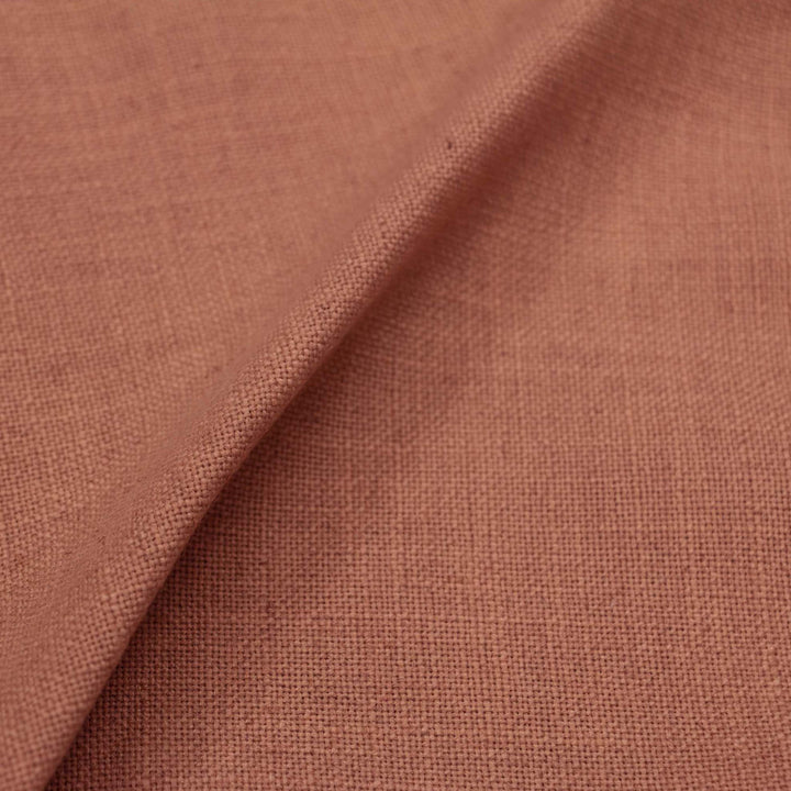 Close-up of terracotta fabric with folded shadowed texture overlap.
