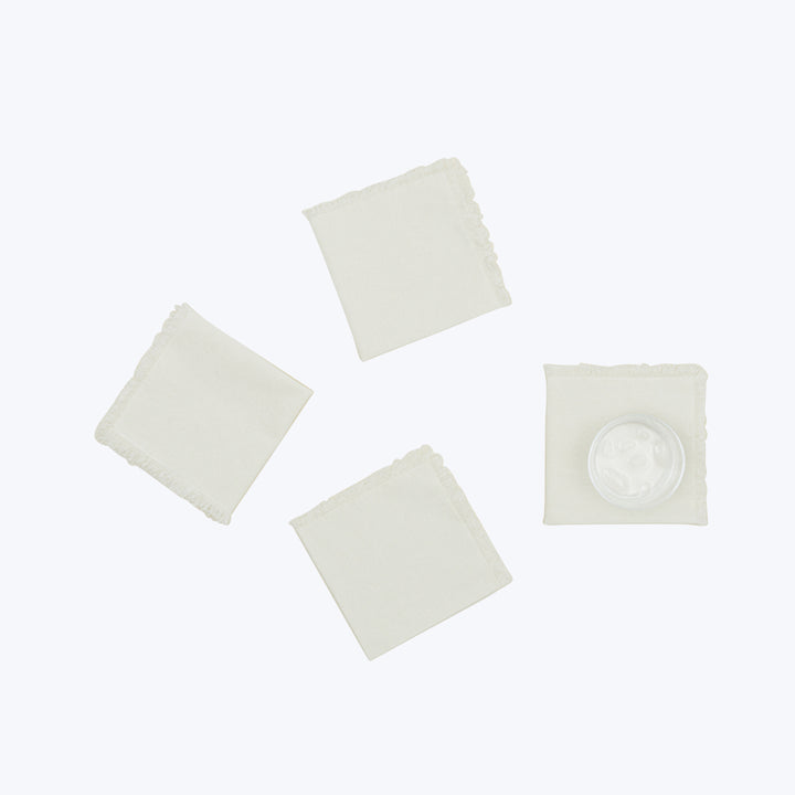 Four off-white squares, one with embossed seal, arranged symmetrically.