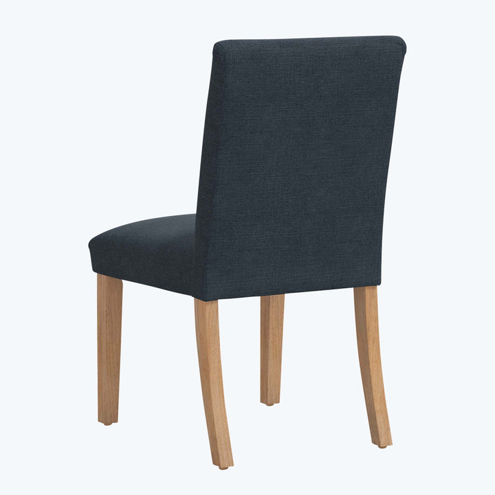 Modern dining chair with navy blue upholstery and light wood legs.