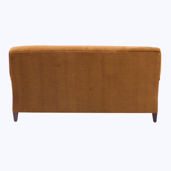 Mustard-yellow ottoman with plush surface and wooden legs, minimalist design.