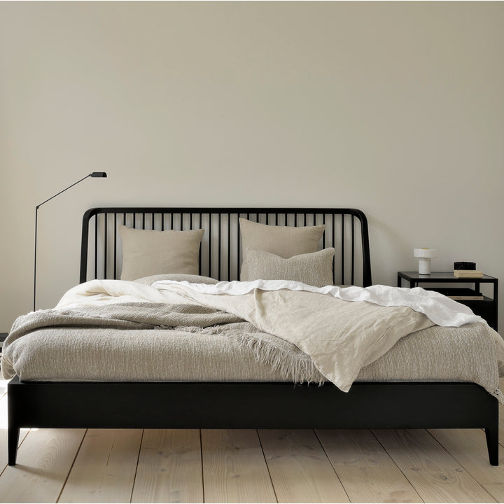 Minimalist bedroom with black metal bed frame and neutral tones.