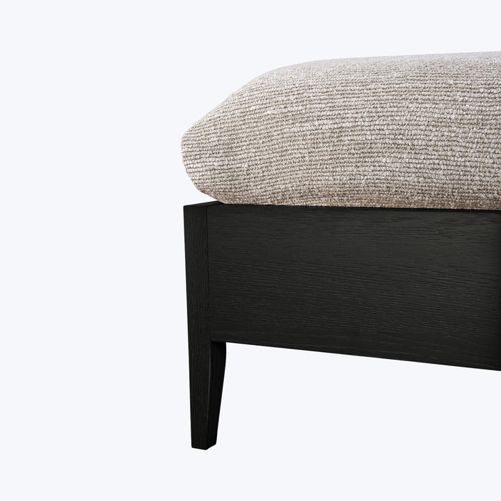 Close-up of dark wood framed furniture with beige textured cushion.