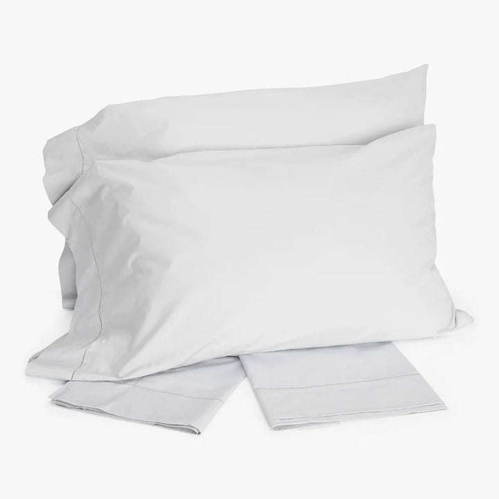 Crisp white bedding set with pillows and sheet detail.