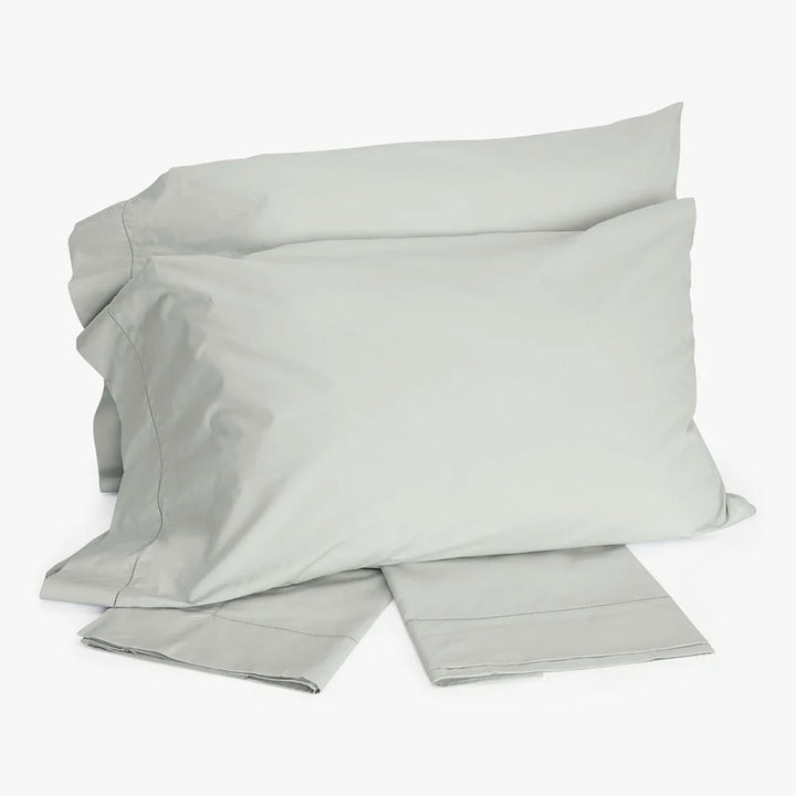 Luxurious bedding set in soft grey color on white background.