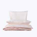 Set of fluffy pillows and folded pink bedding on display.