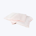 Two folded pillowcases in pink and white against white background.