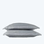 Two soft gray pillows stacked on white background, studio setting.
