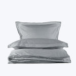 Neatly folded light gray bedding set on white background display