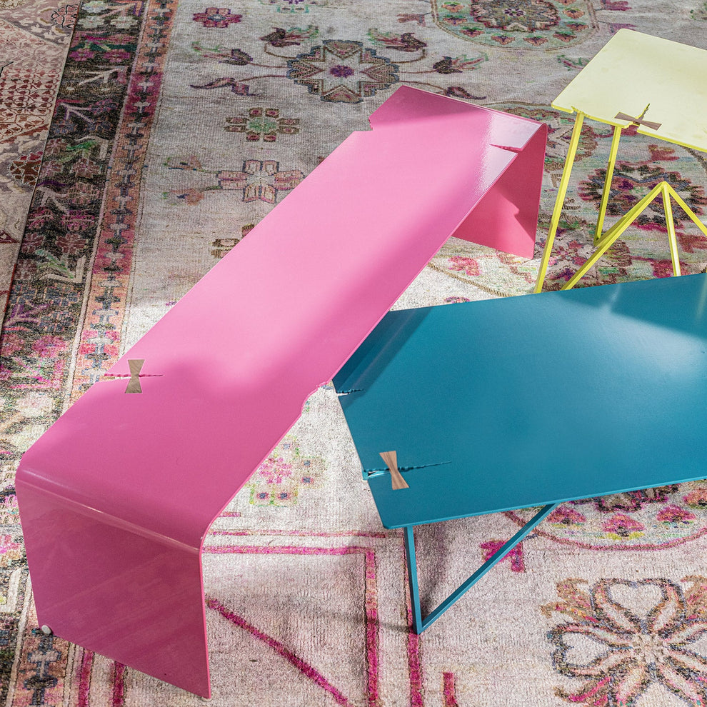Modern tables in vibrant colors contrast with classic patterned carpet.