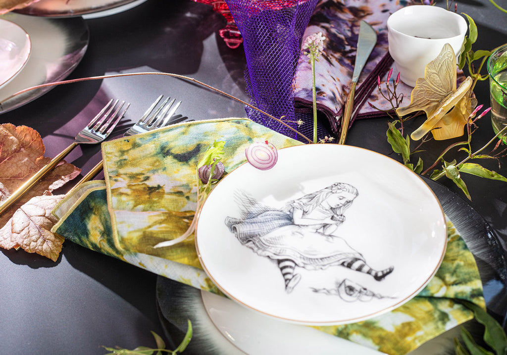 Artistic table setting with woman illustration, gold accents, and natural elements.