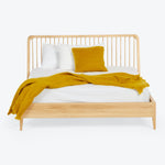 Modern wooden bed dressed in white bedding with mustard accents.