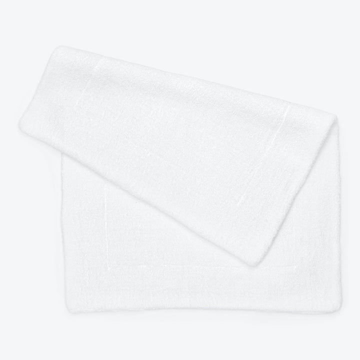 Neatly folded, plush white towel against a minimalist background.