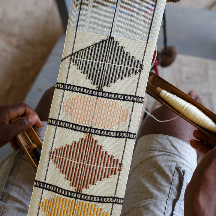 Skilled weaver creates intricate fabric on traditional handloom in workshop.