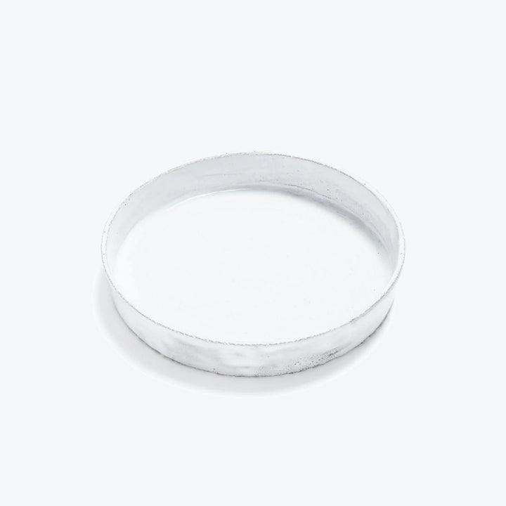 Simple white ceramic plate on white background, top-down view.